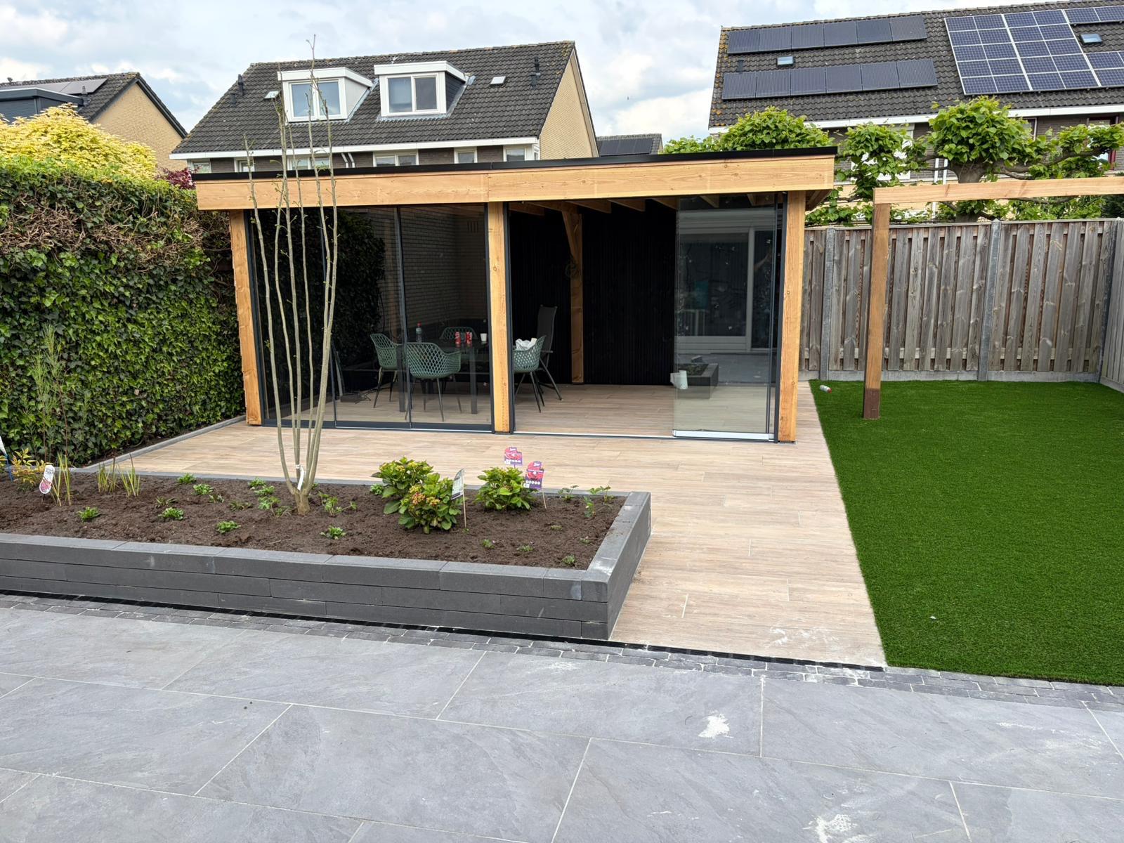 Afgewerkte houten veranda met glazen schuifwanden in de tuin